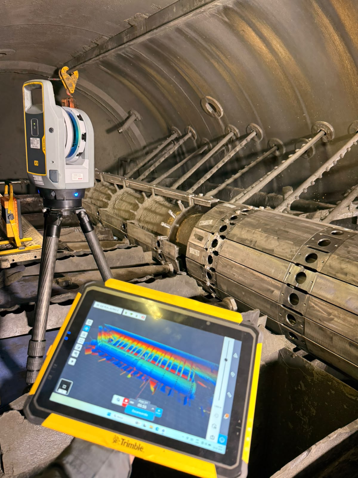 Escáner láser Trimble X9 dentro de un ducto industrial, con nube de puntos en tablet